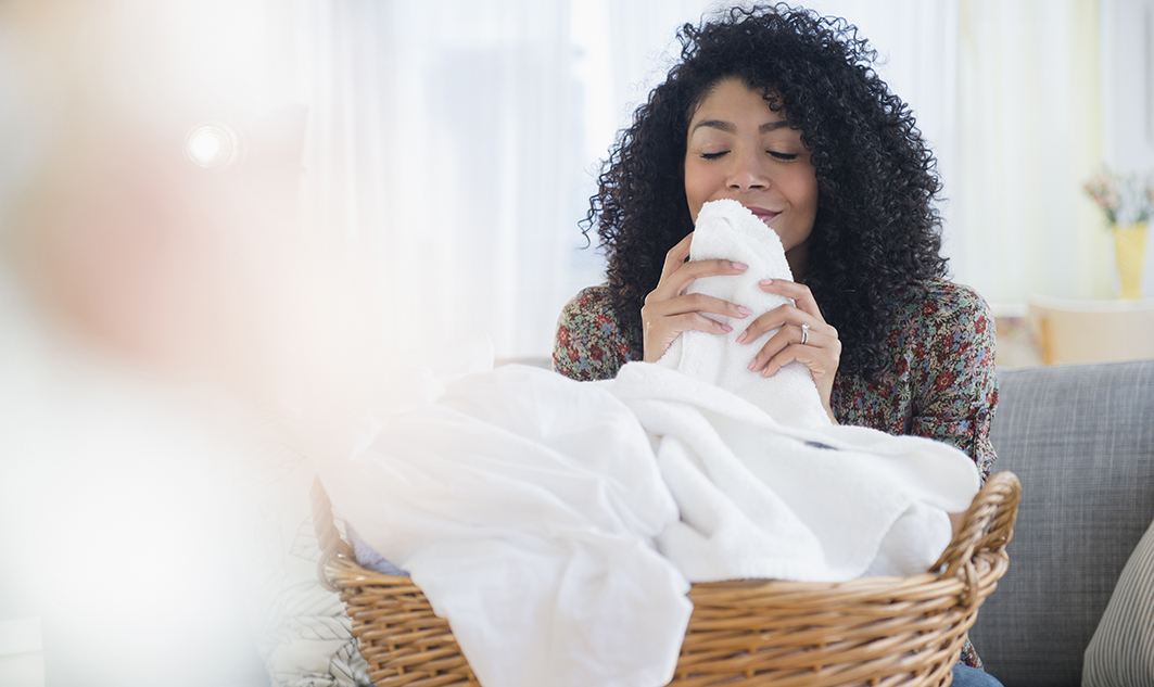 young African American woman smelling freshly washed towels